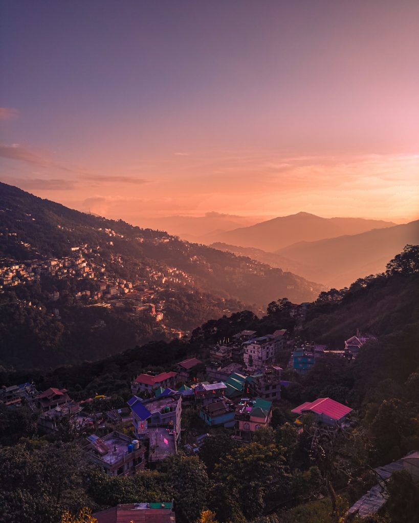 Photo by Akash Pratap Singh a sunset view of a small town on a hill
